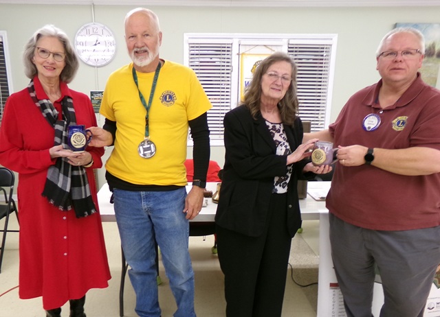 Two representatives of the Cullman Master Gardeners receive mugs from two Lions Club members.