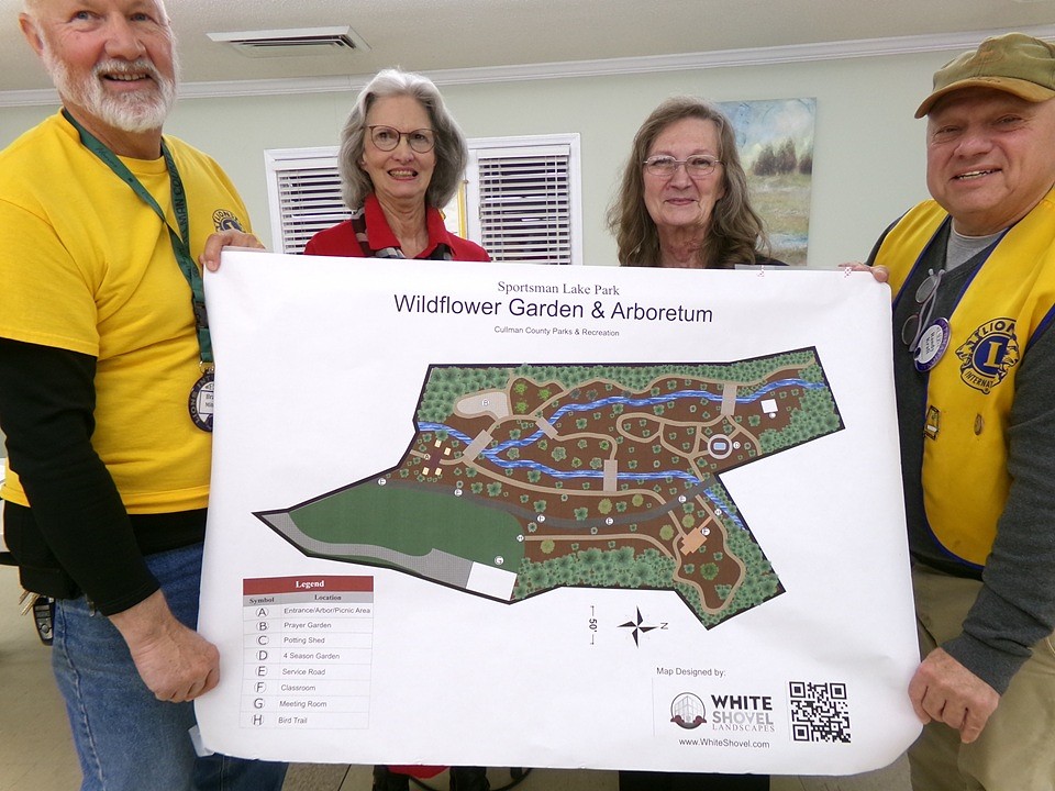 Master Gardeners and Lions Club members hold a detailed map of the Wildflower Garden and Arboretum.