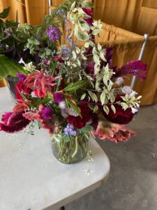 Multiple colorful flowers and foliage in a clear vase.